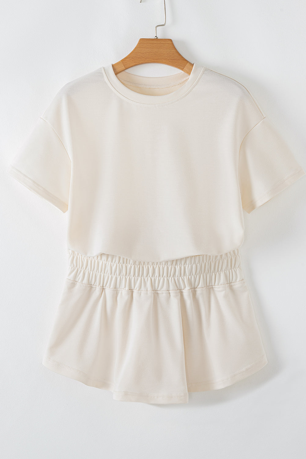 Beige top on a wooden hanger against a white background