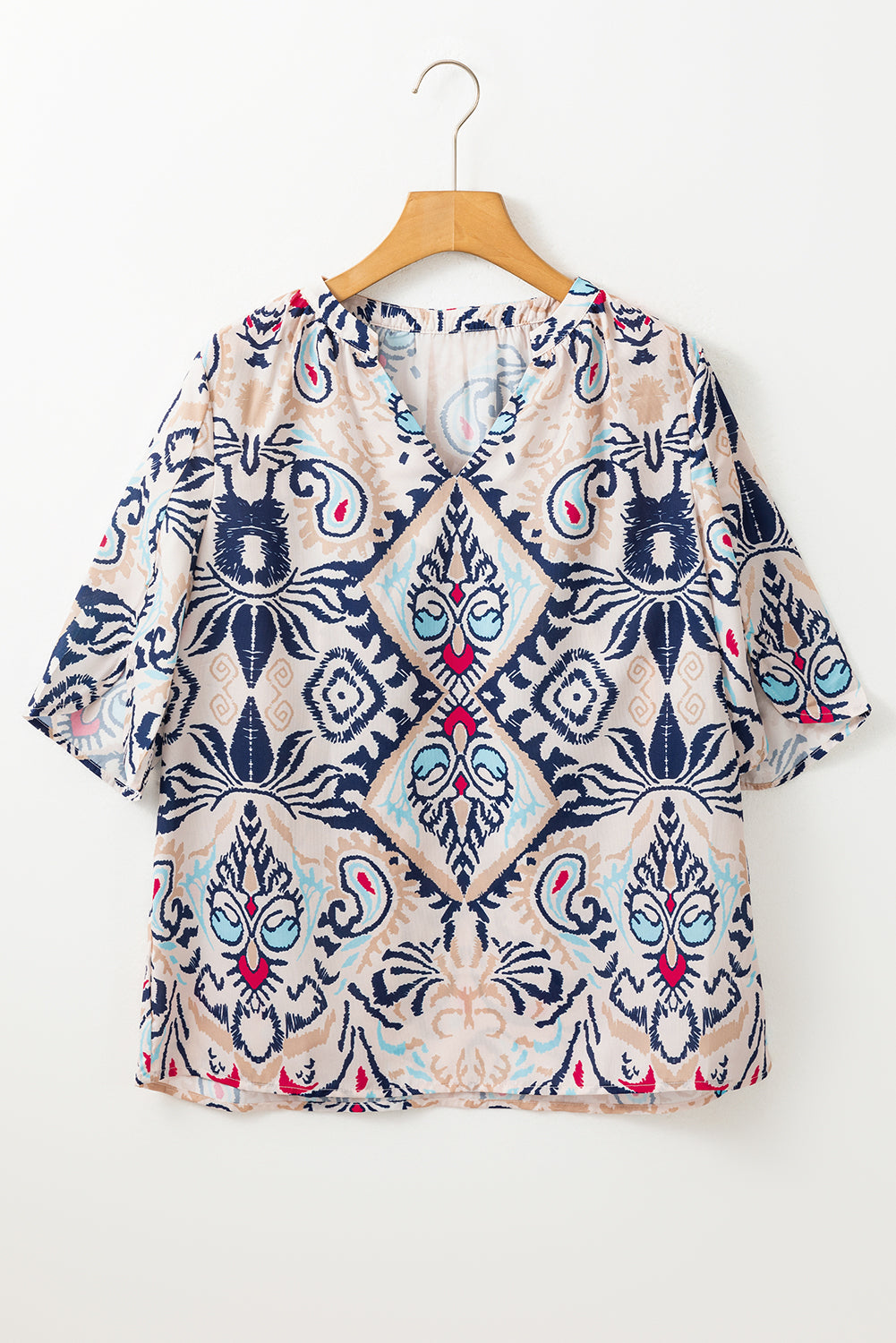 Patterned blouse on a wooden hanger against a white background