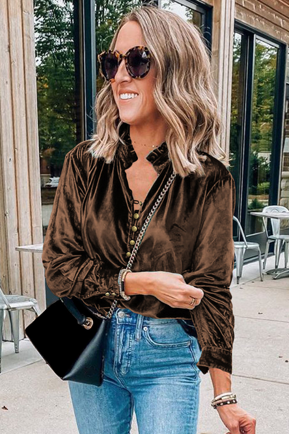 Woman wearing a brown velvet shirt and blue jeans, standing outdoors.