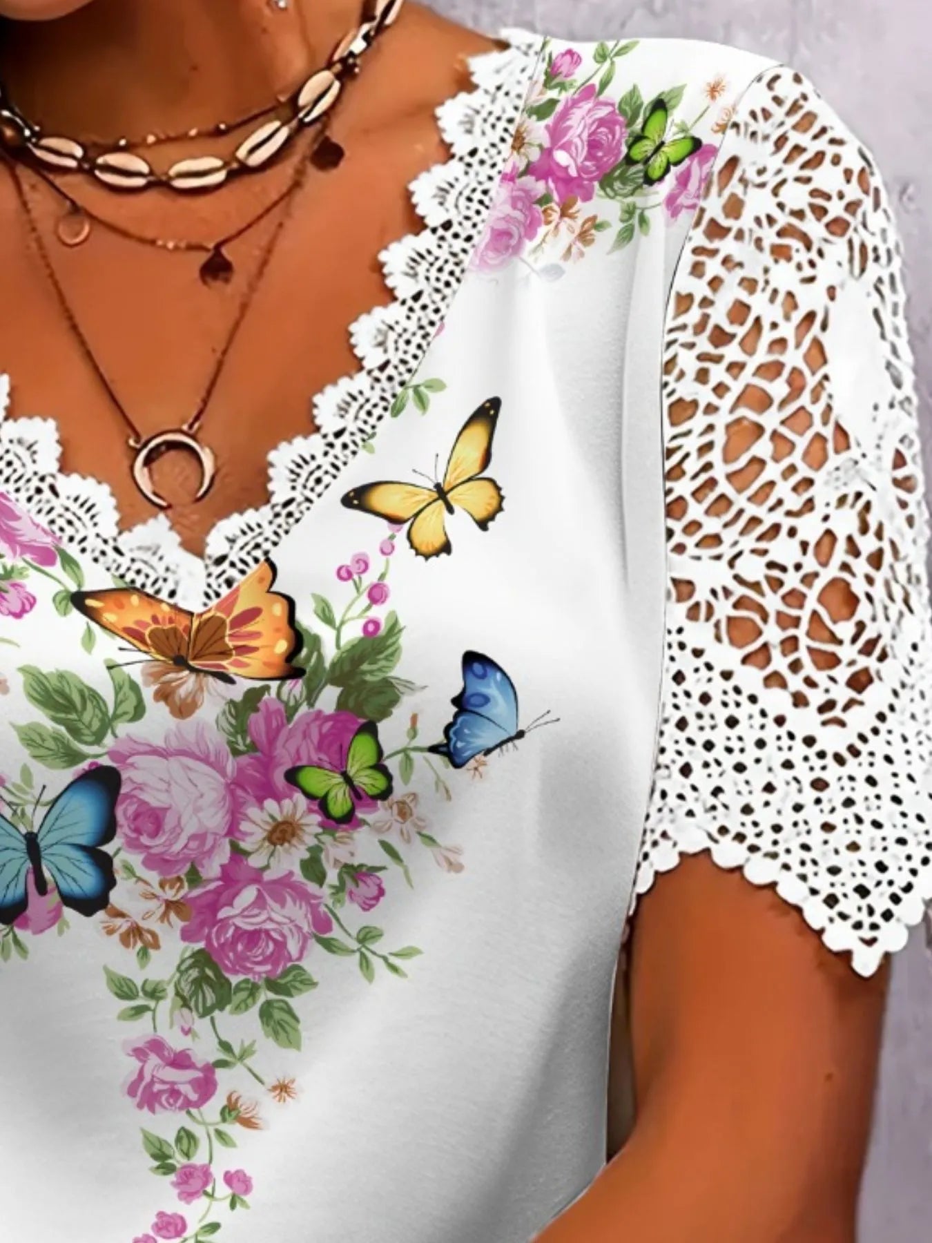 White blouse with floral and butterfly patterns on a plain background