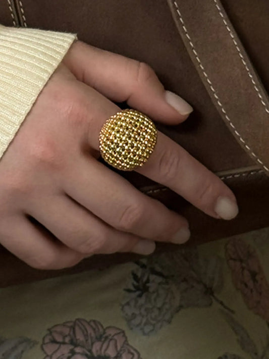 Gold ring on a finger with a floral-patterned fabric background