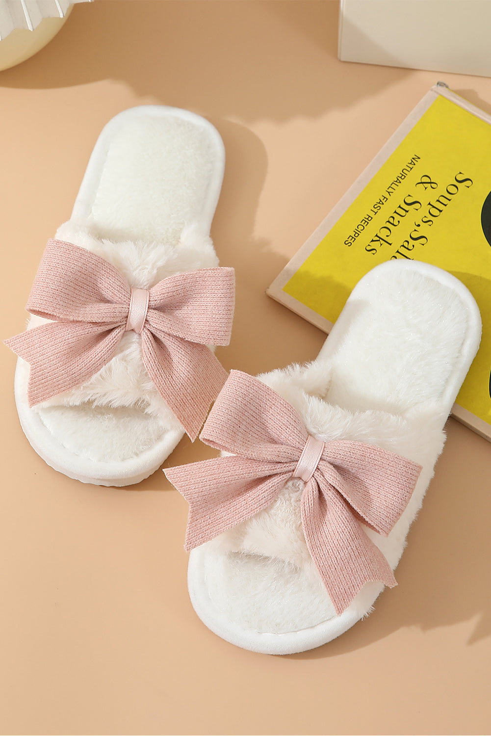 White slippers with pink bows on a beige surface