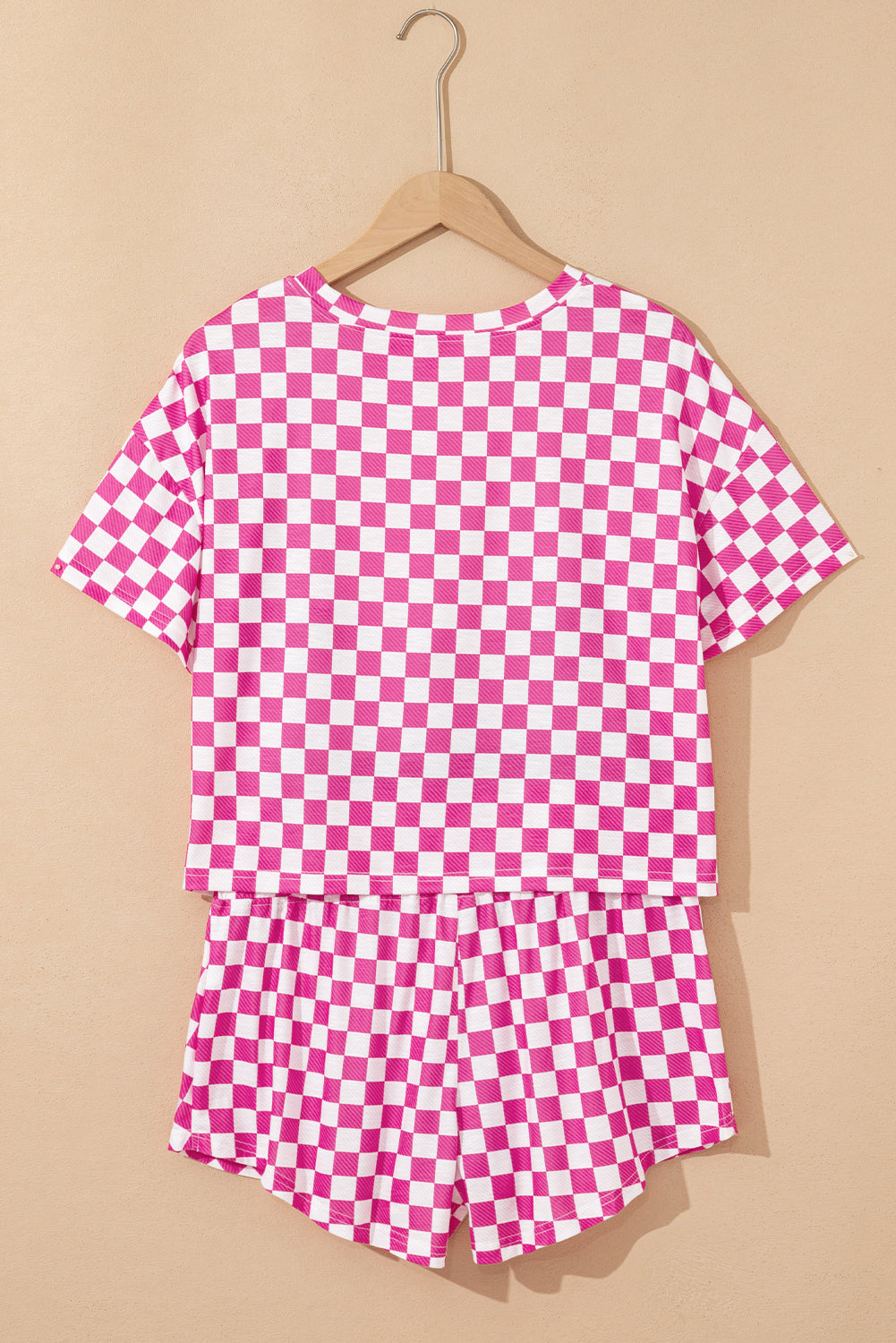 Pink and white checkered shirt on a hanger against a beige background
