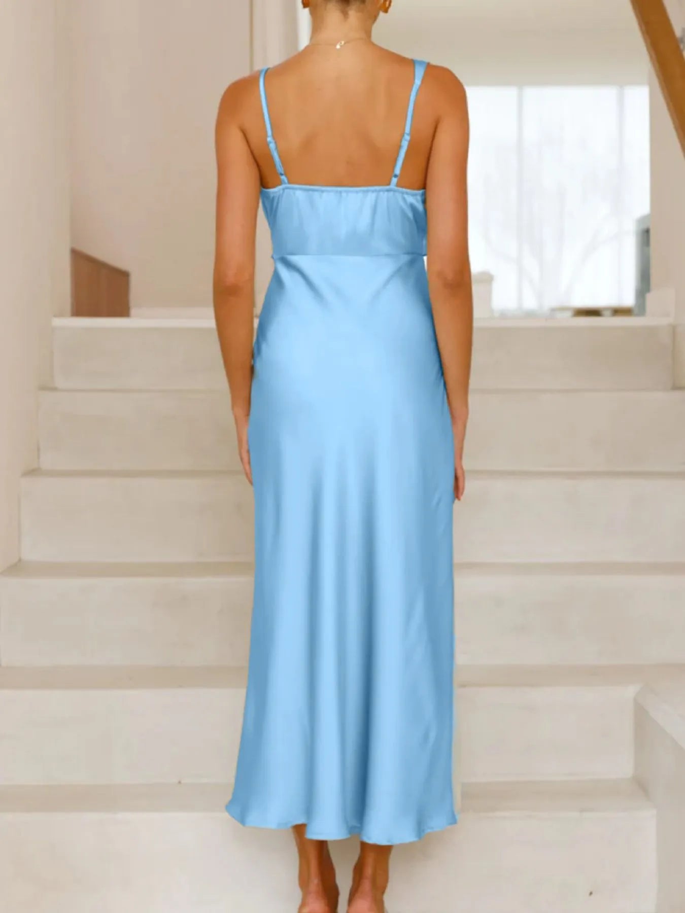 Woman wearing a light blue dress standing on a staircase.