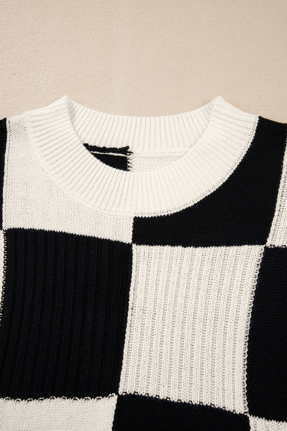 black and white checkered sweater against a pink background