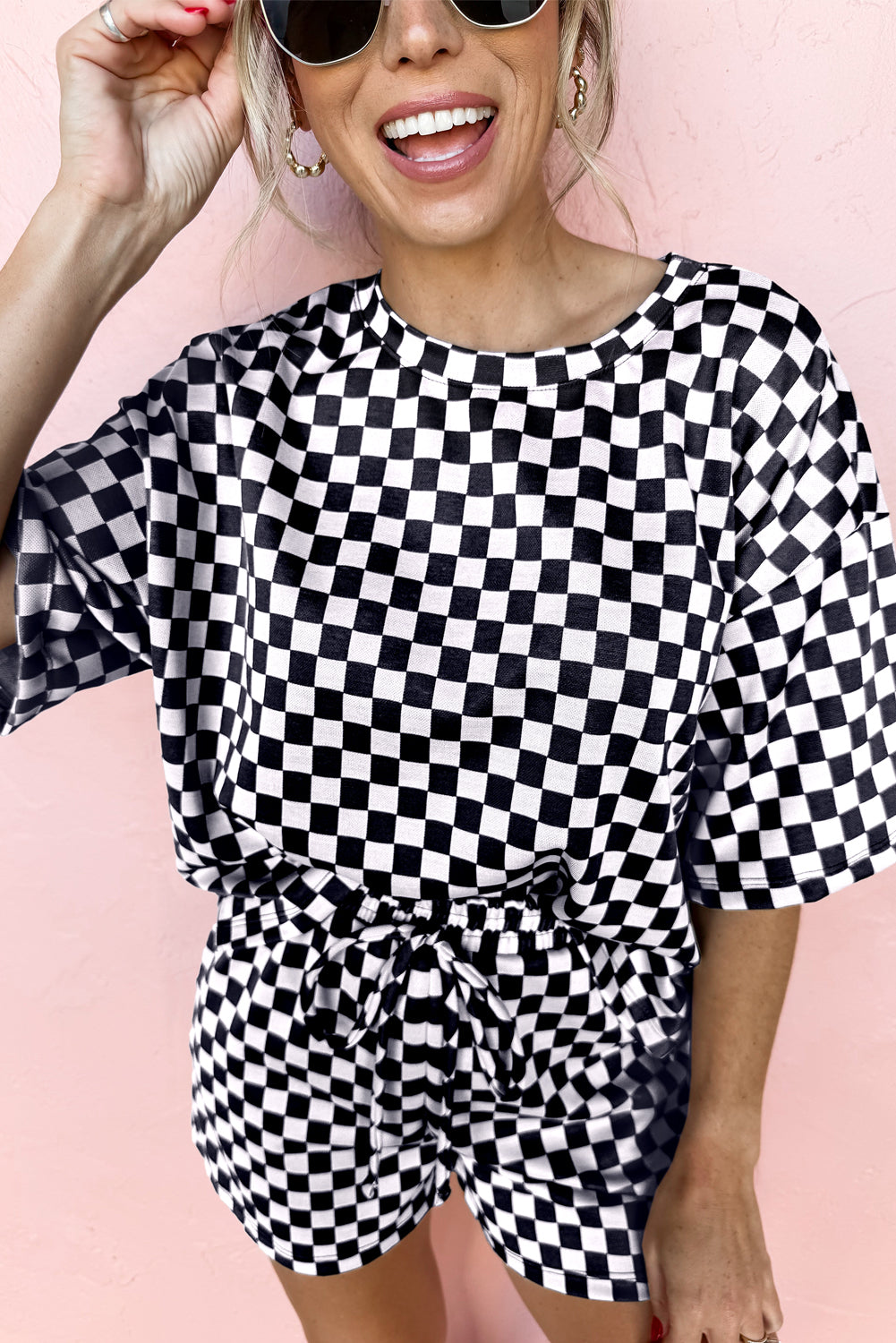 Woman wearing a black and white checkered outfit against a pink background