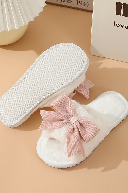 White slippers with pink bows on a beige surface