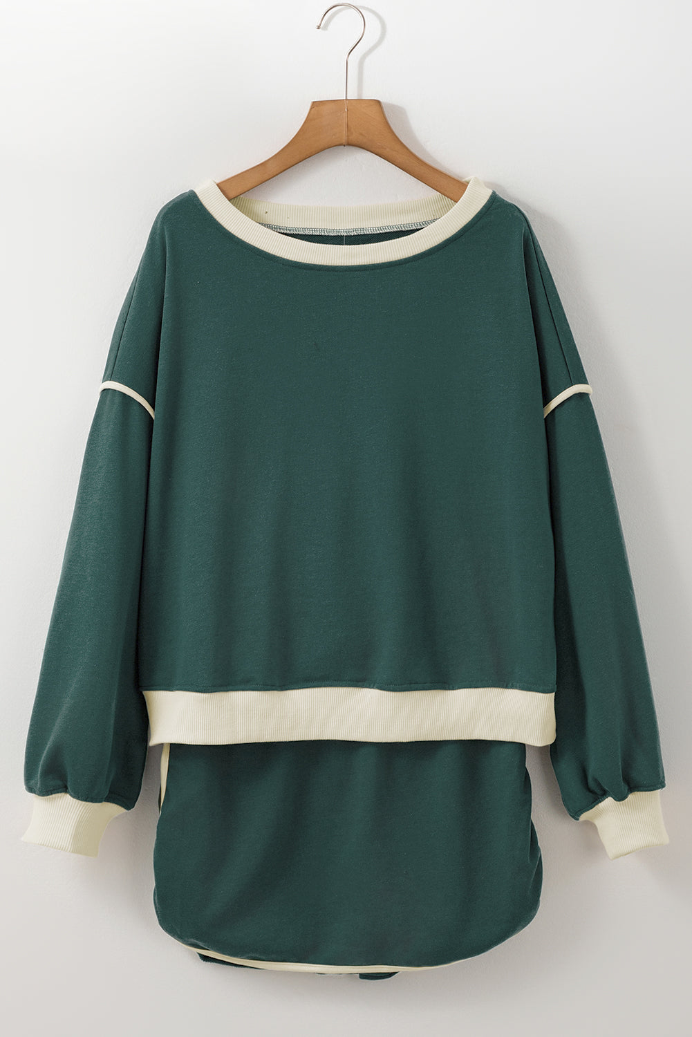 Green sweater with white trim on a wooden hanger against a white background