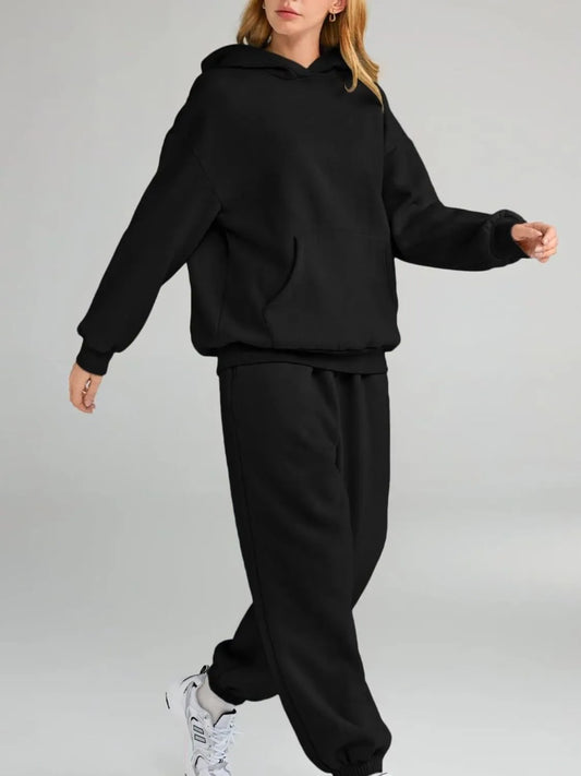 Person wearing a black hoodie and black pants on a gray background