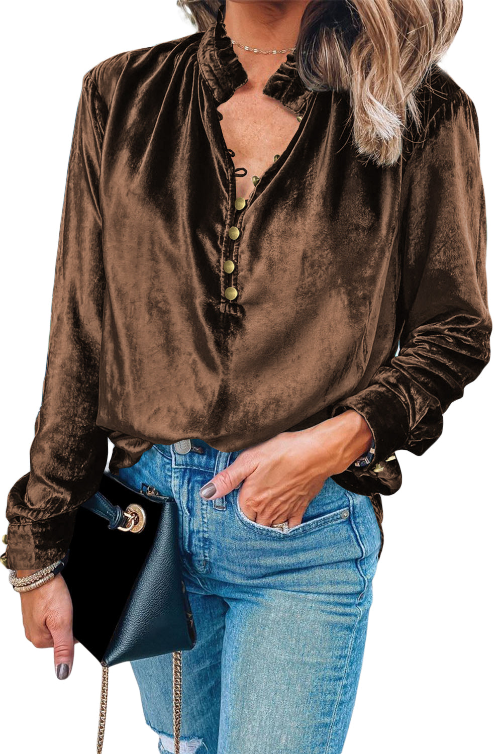 Person wearing a brown velvet shirt and blue jeans with a black handbag.