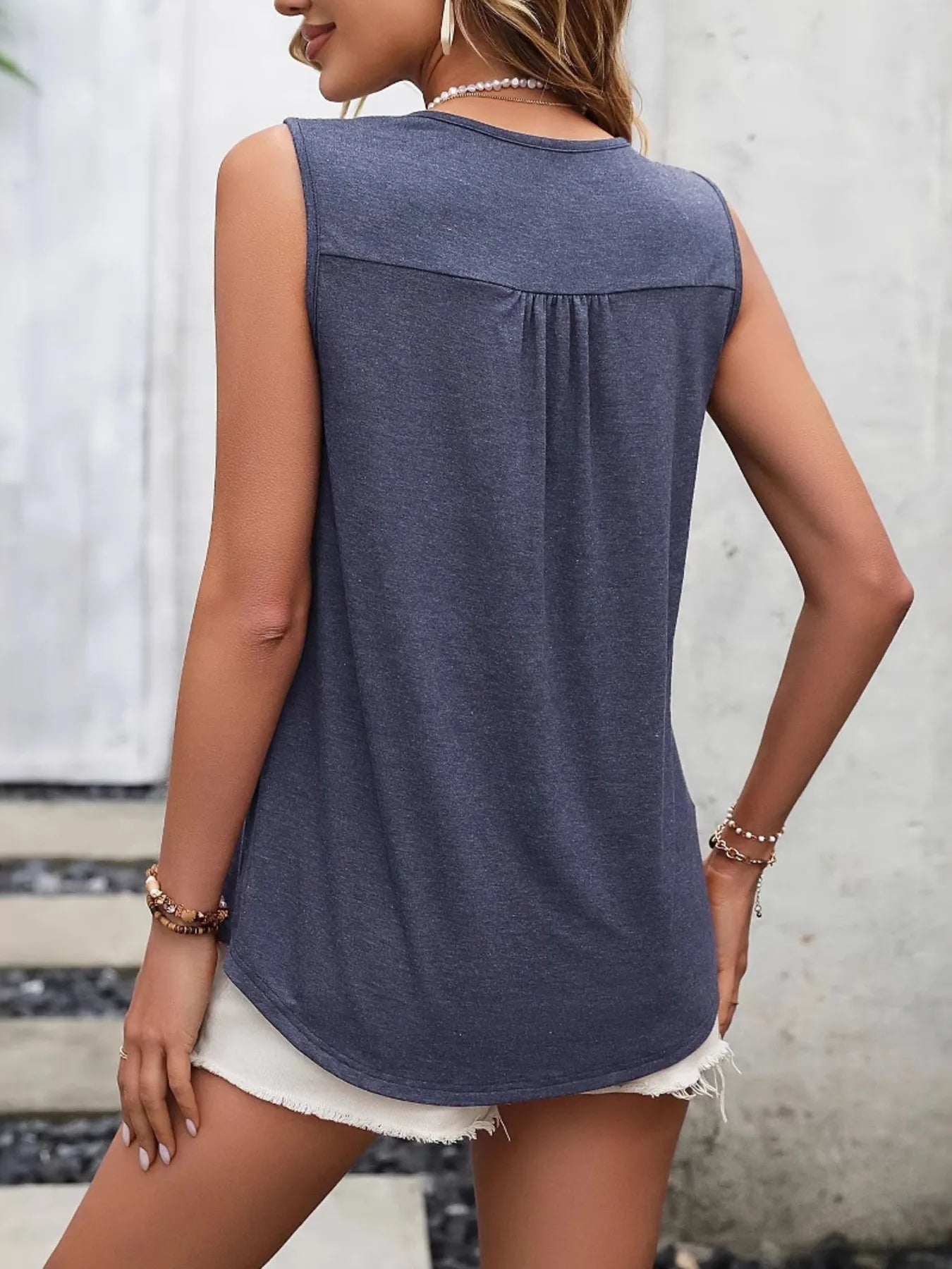 Woman wearing a blue sleeveless top with a neutral background