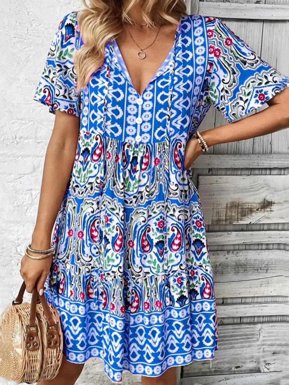 Woman wearing a colorful patterned dress with a white brick wall background