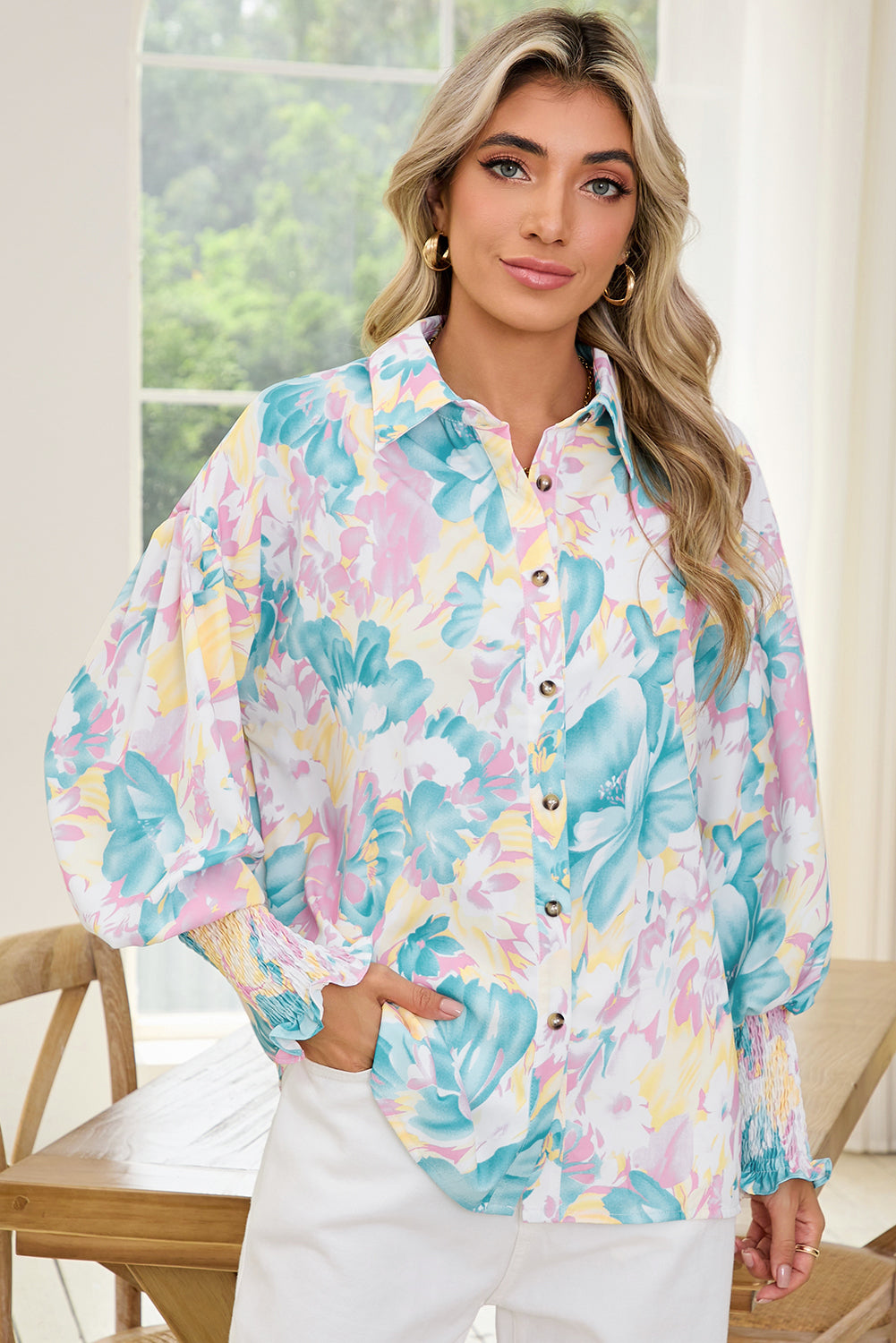 Woman wearing a colorful floral blouse in a bright room.