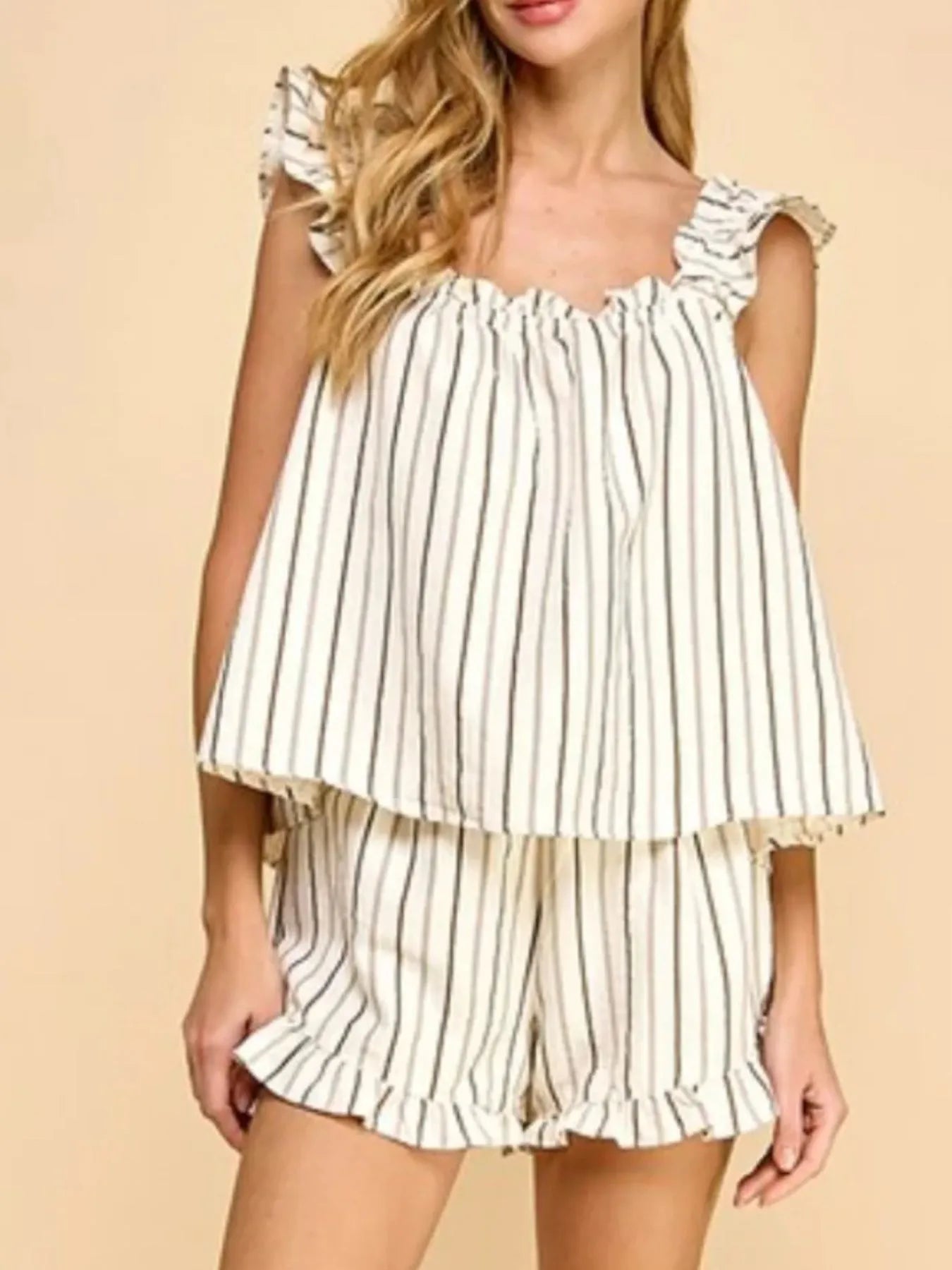 Woman wearing a white and black striped top and shorts set on a beige background