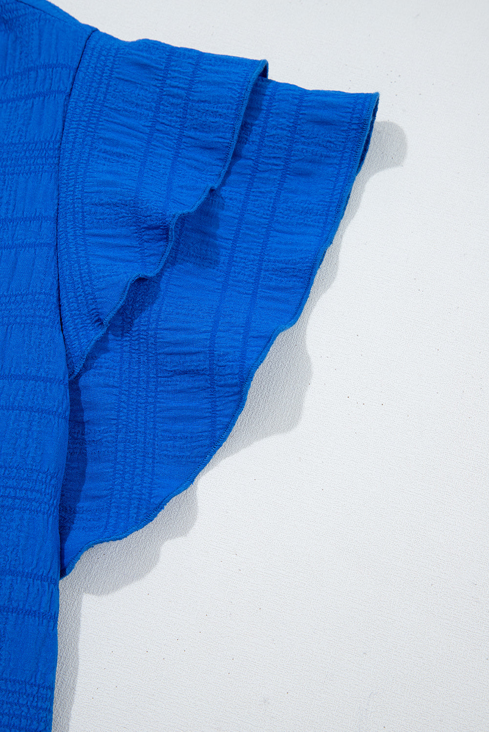Close-up of a blue textured fabric with ruffled edge on a white background