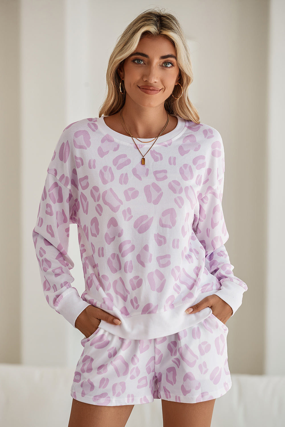 Woman wearing a pink leopard print pajama set against a plain background