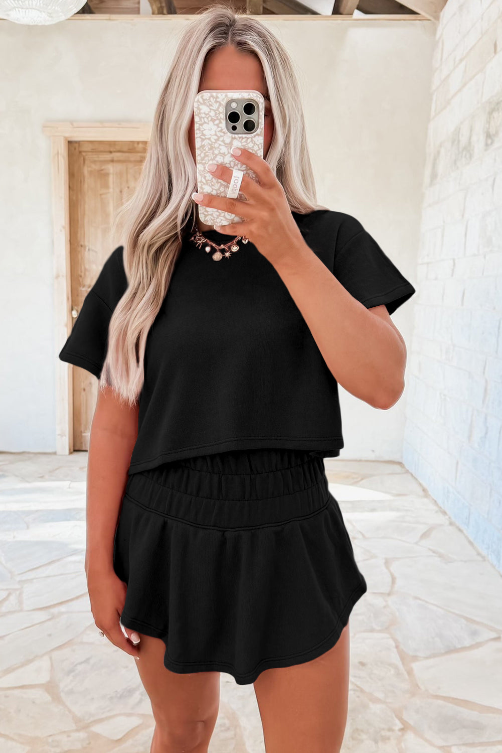 Person wearing a black outfit taking a mirror selfie.