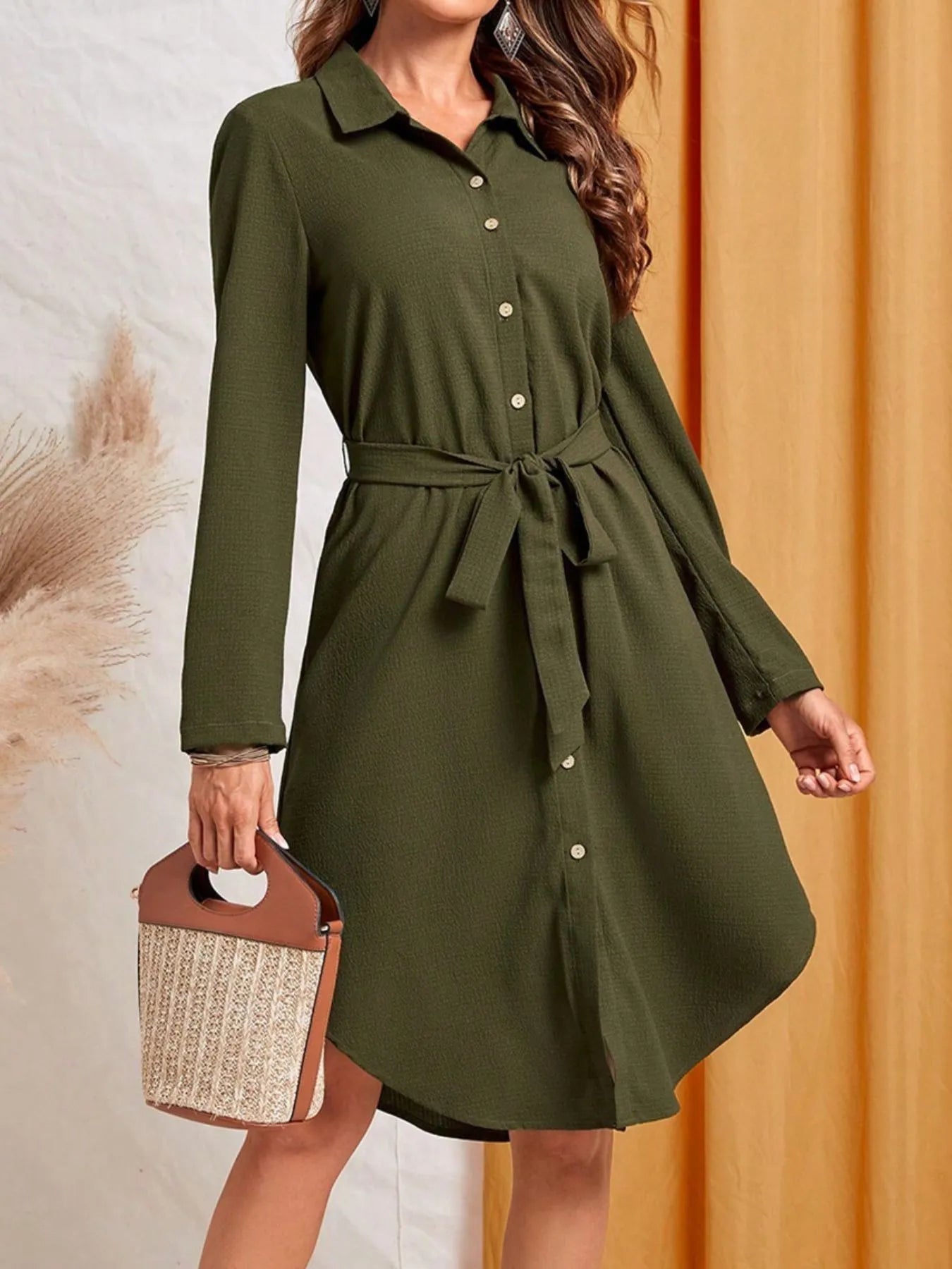 Green dress with a belt worn by a person against a neutral background