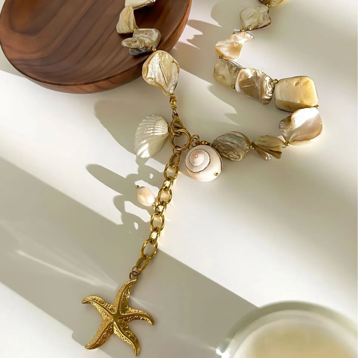 Necklace with shell and starfish charms on a light surface