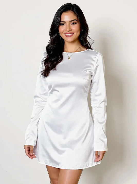 Woman wearing a white long-sleeve dress against a plain background