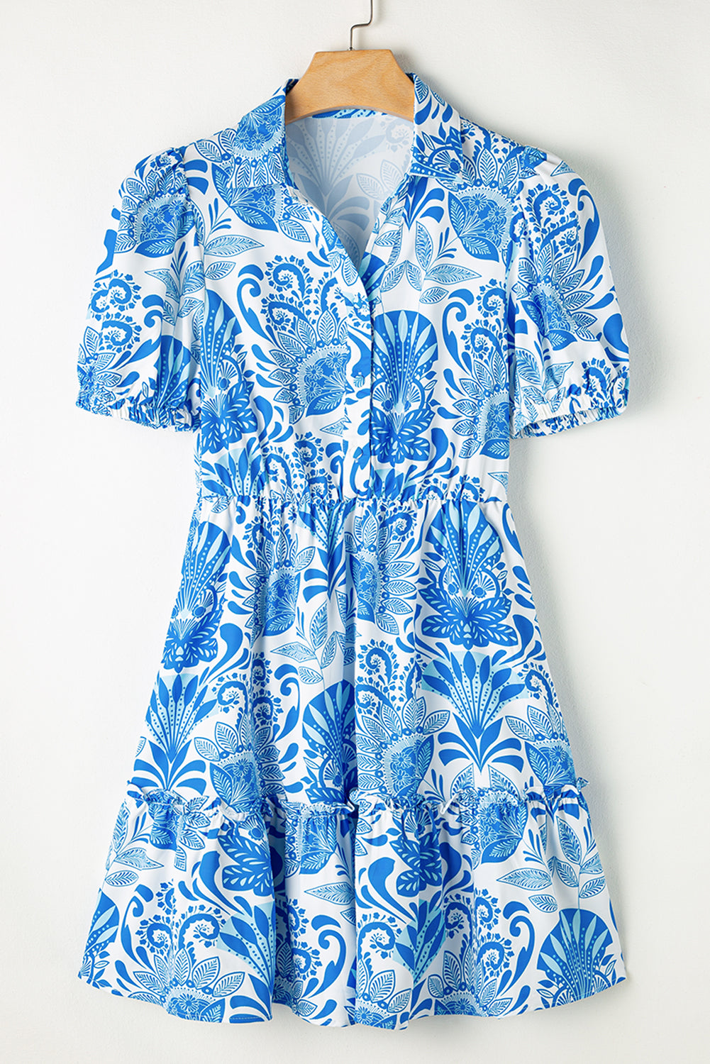 Blue and white floral patterned dress on a hanger against a white background