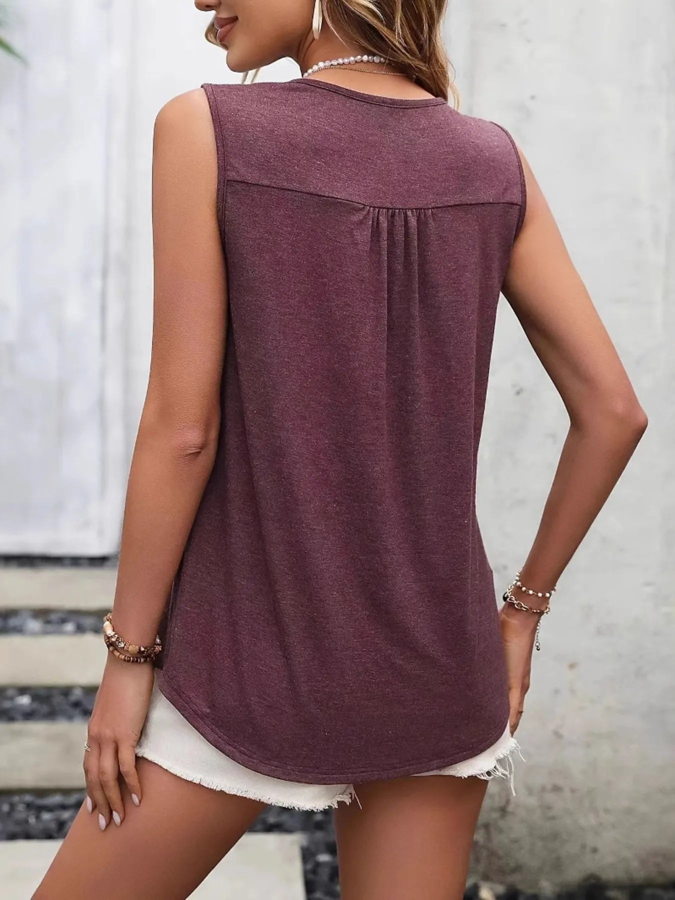 Woman wearing a sleeveless maroon top with a blurred background