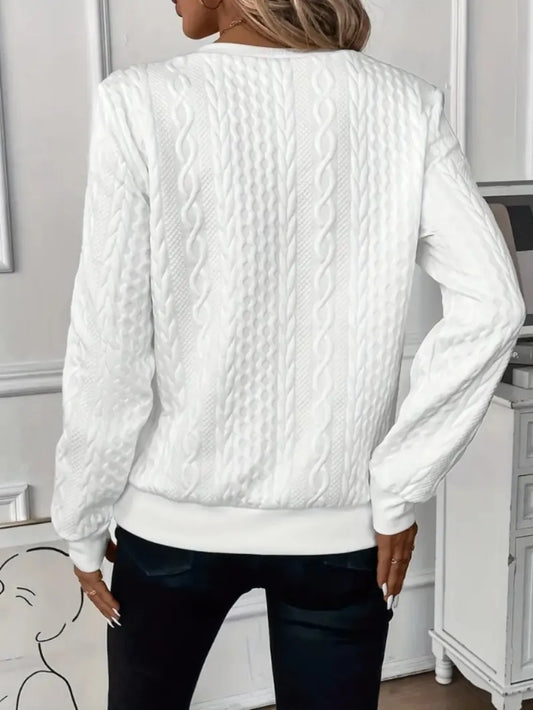 Person wearing a white cable knit sweater in an indoor setting