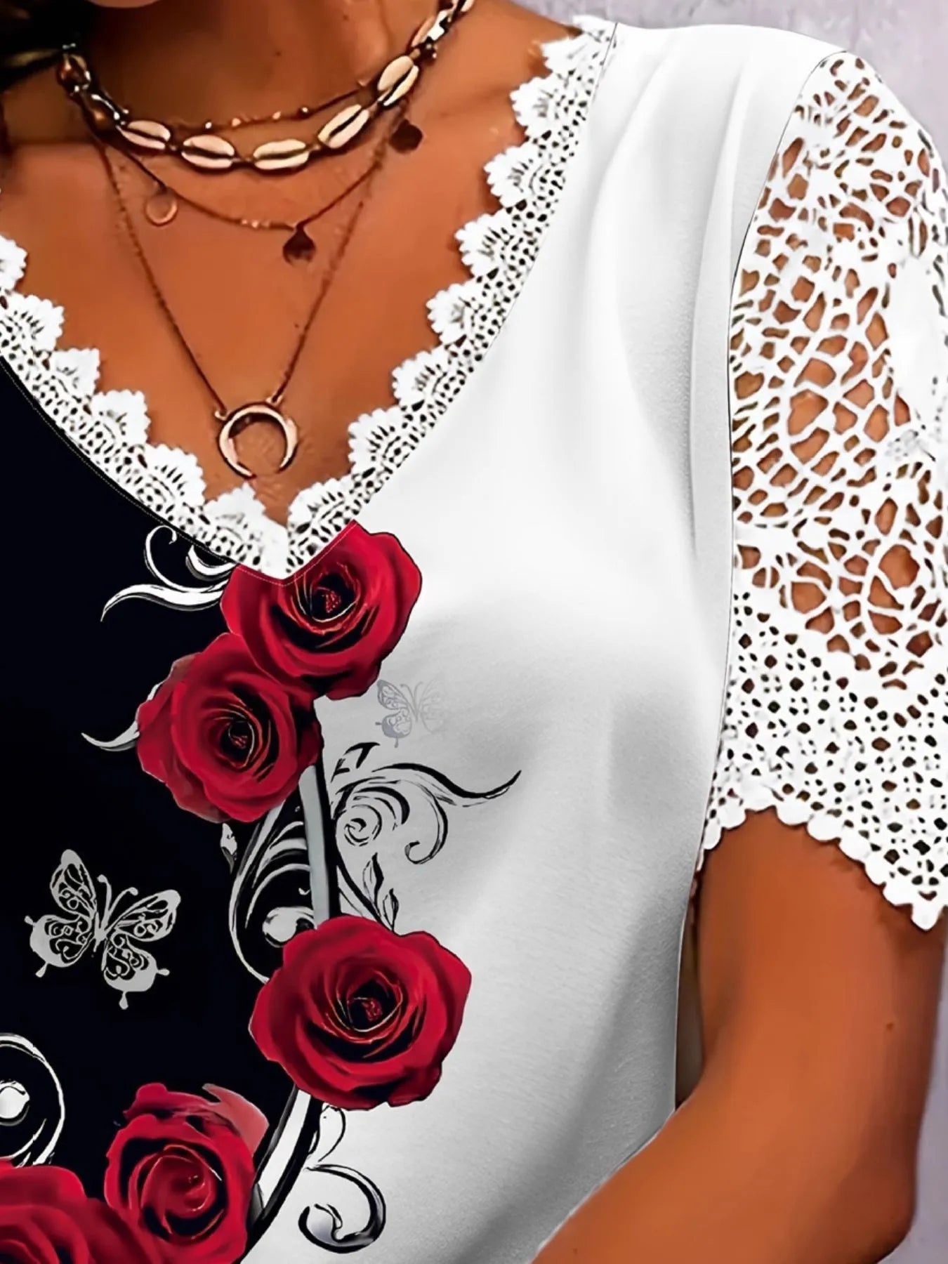 Close-up of a white lace-trimmed top with red roses and butterfly design.