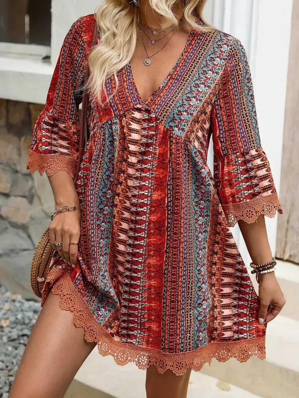 Woman wearing a colorful patterned dress with lace details outdoors.