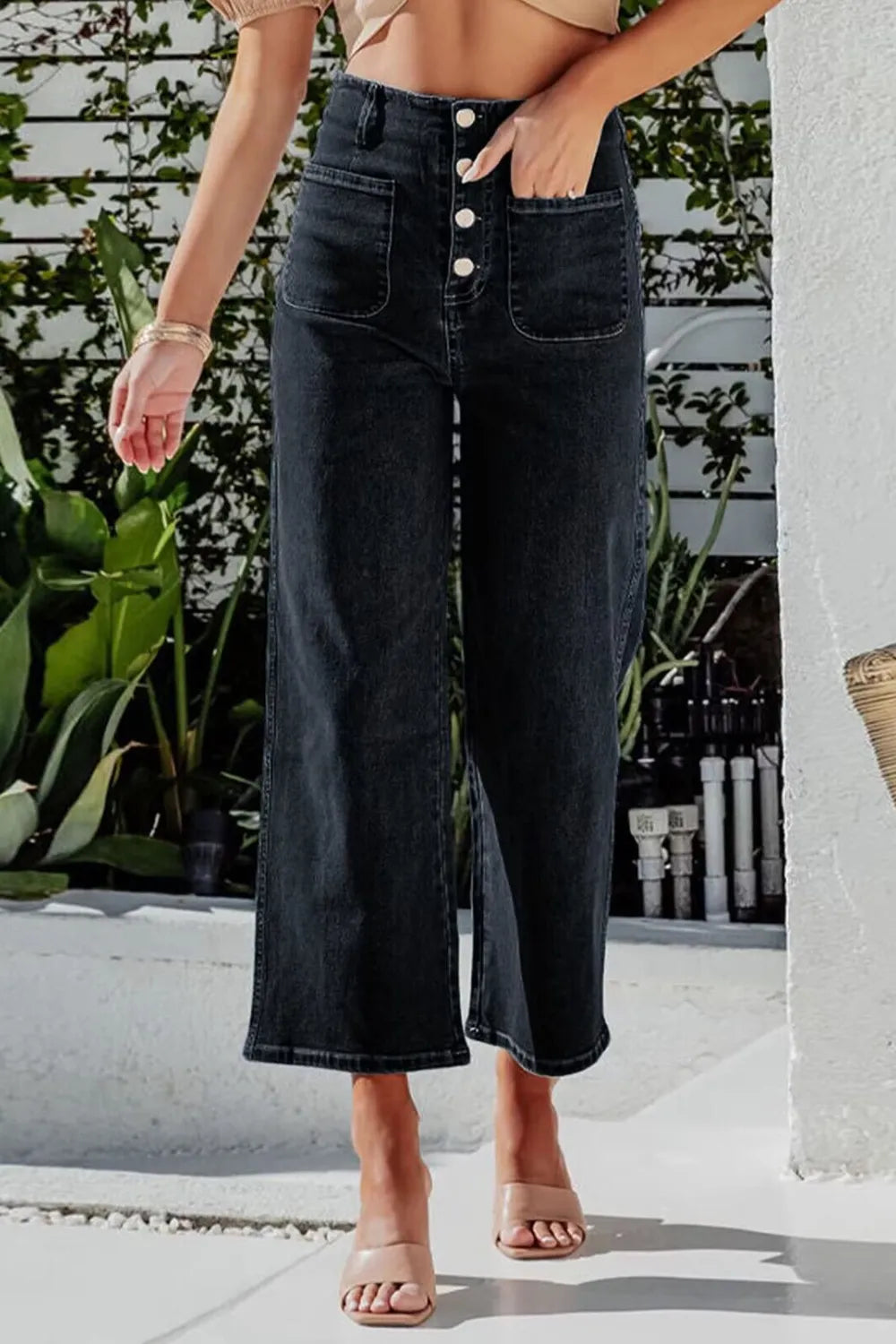 Person wearing black wide-leg jeans with a blurred outdoor background