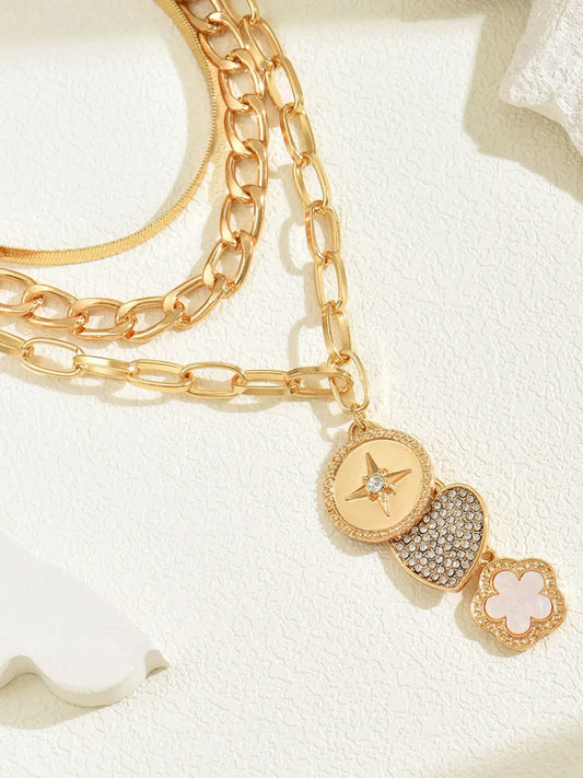 Gold chain bracelet with decorative charms on a light background