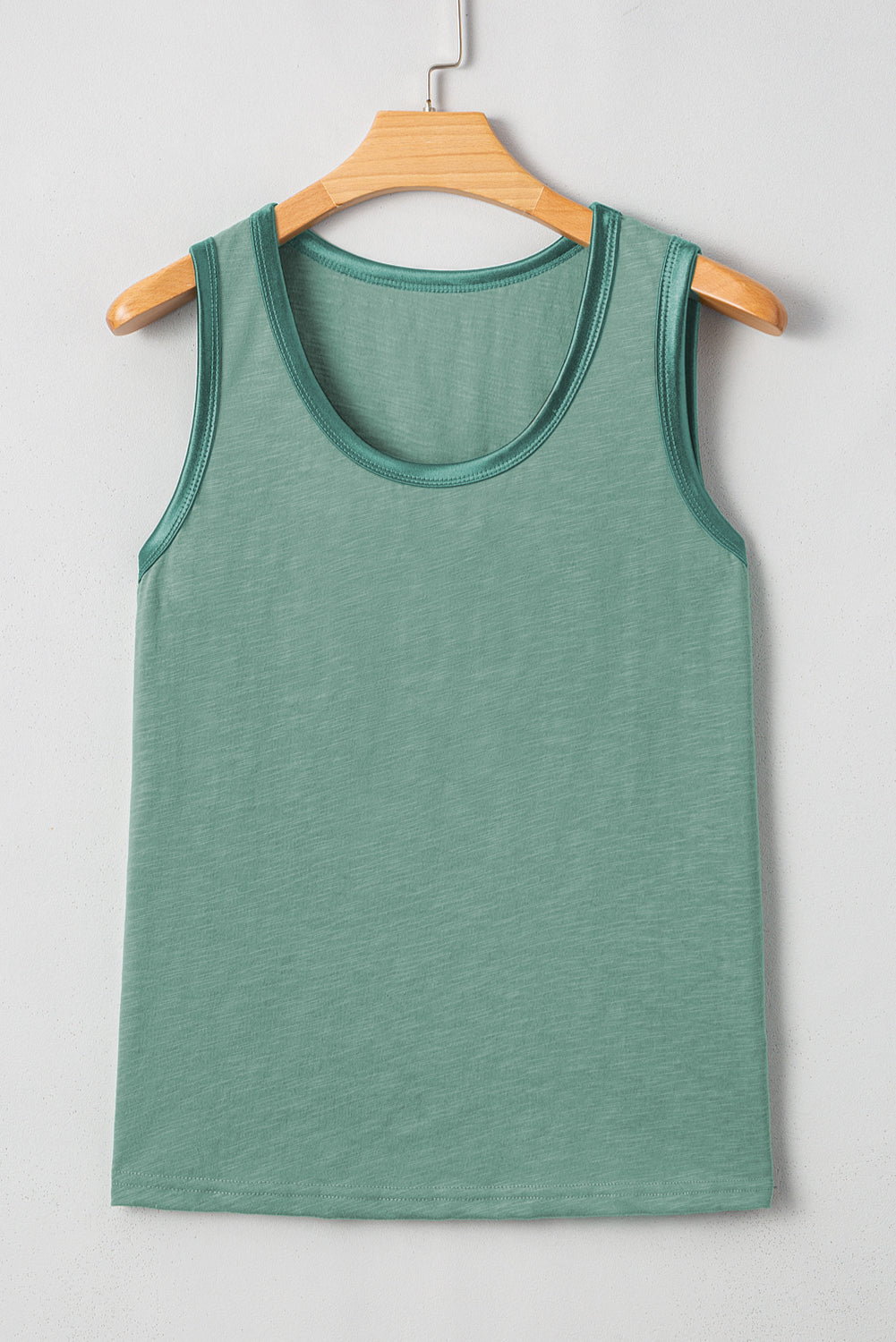Green tank top on a wooden hanger against a white background