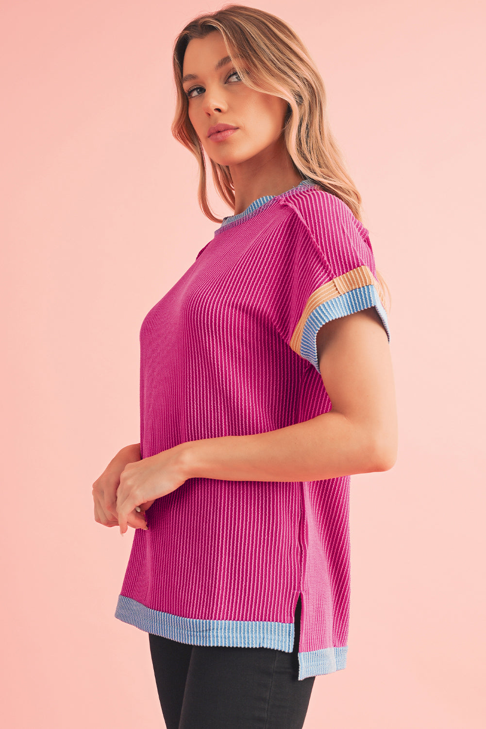 Woman wearing a pink ribbed sweater with colorful sleeves on a pink background