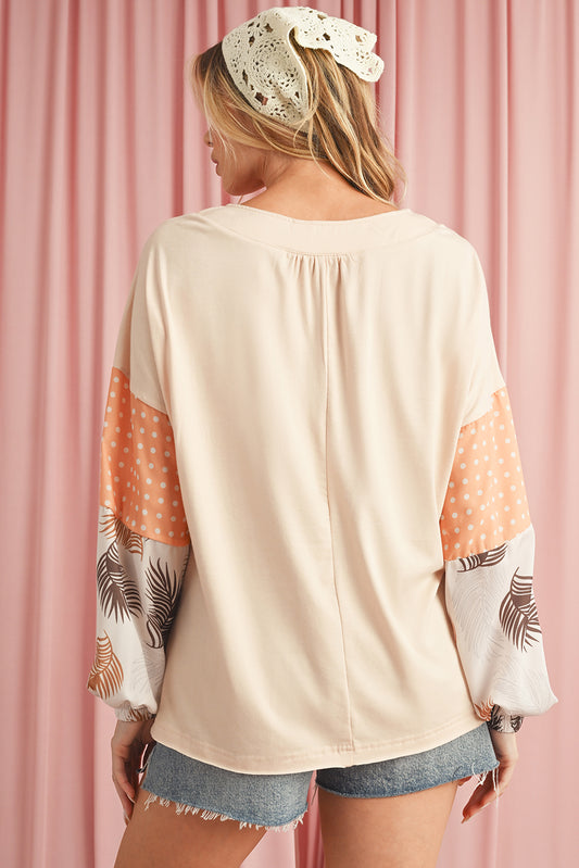 Woman wearing a beige blouse with colorful sleeves against a pink curtain background