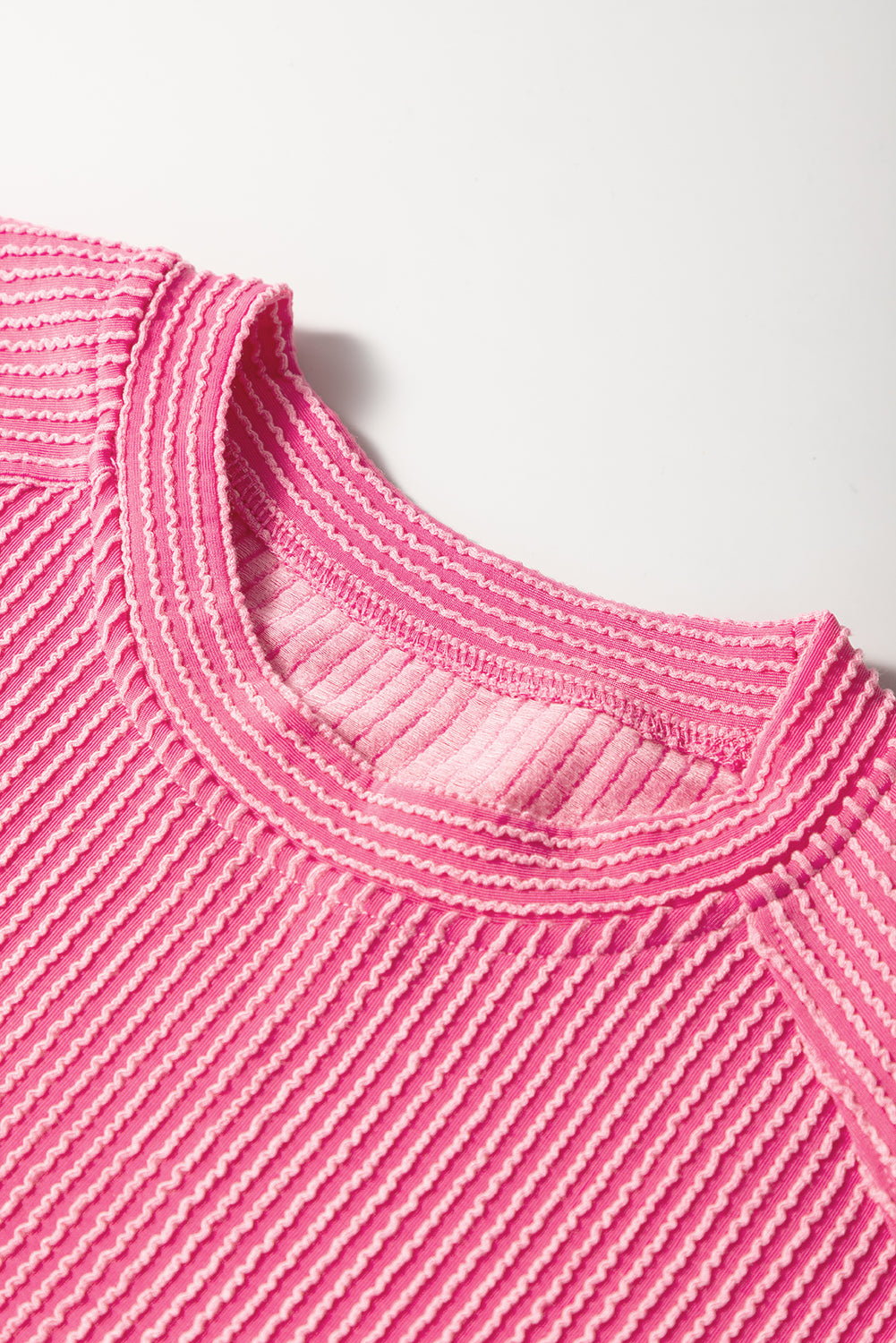 Close-up of a pink textured sweater collar on a light background