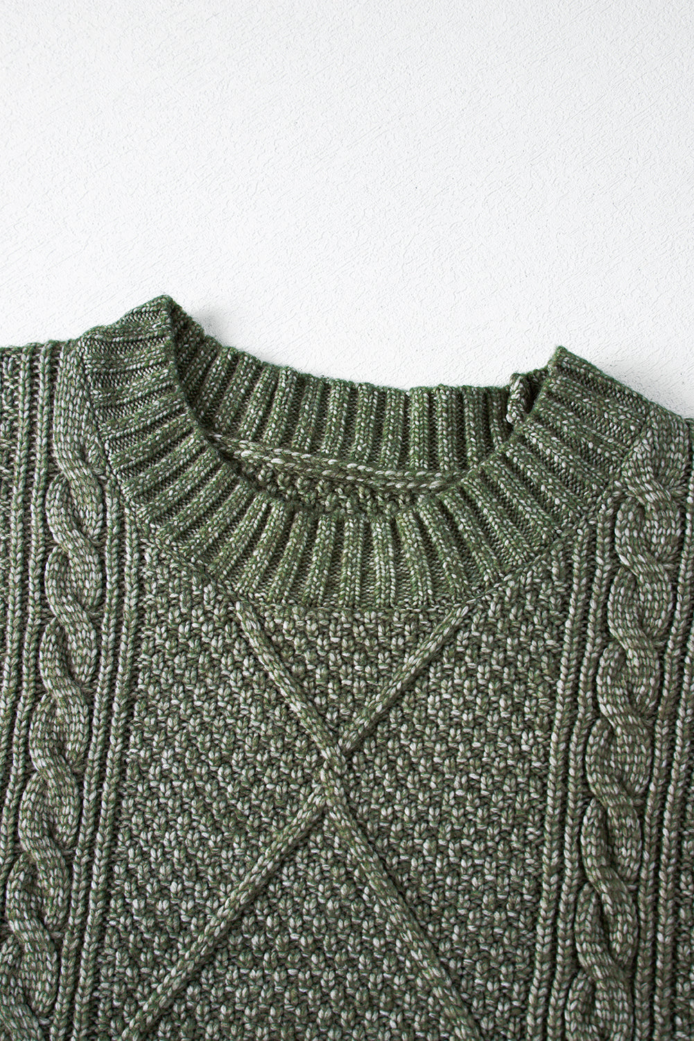 Close-up of a green cable knit sweater on a white background