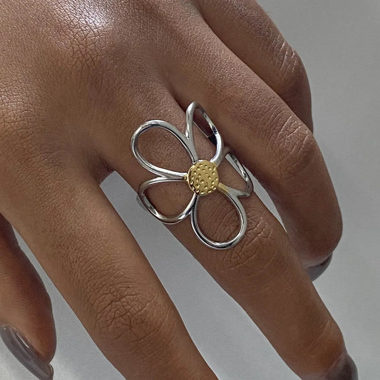 Silver ring with a gold center on a person's finger against a neutral background