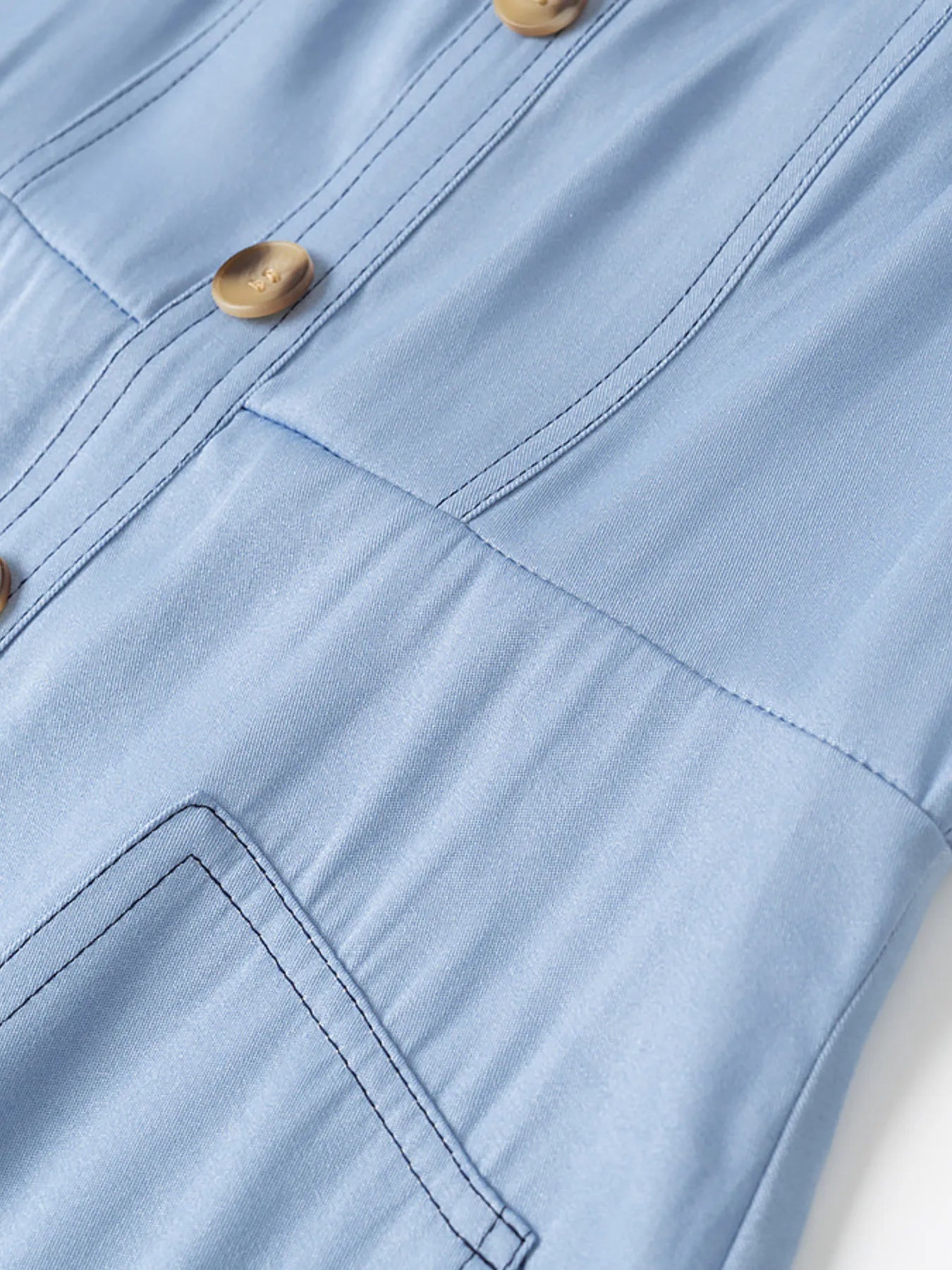 Close-up of a light blue shirt with buttons and stitching details.