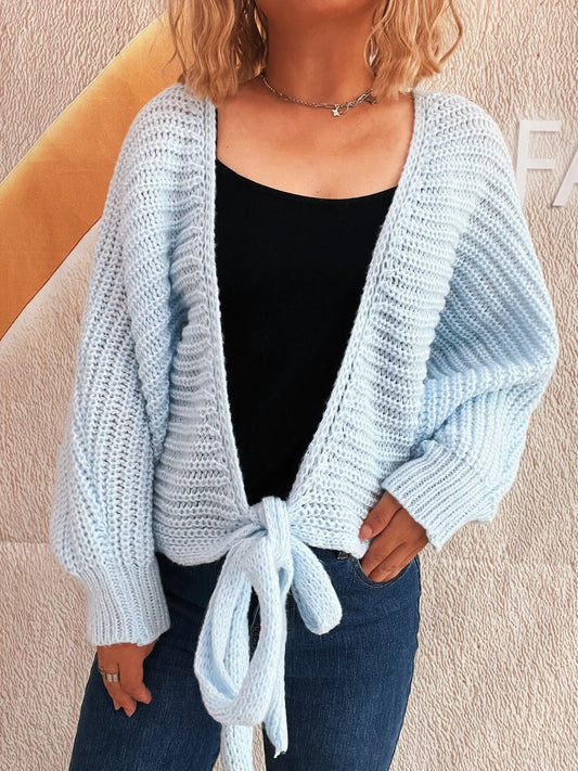 Light blue knitted cardigan worn by a person against a beige background