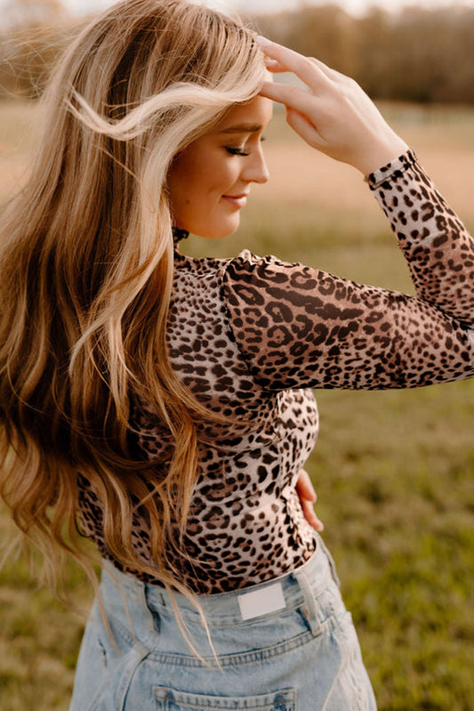 Woman wearing a leopard print top and denim shorts in an outdoor setting