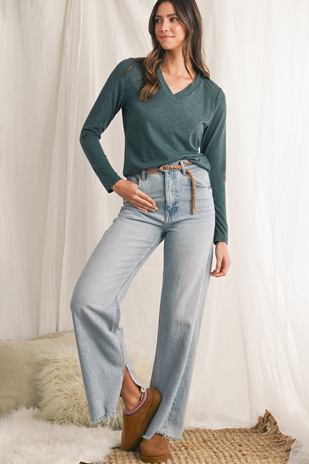 Woman wearing a green sweater and jeans against a white background