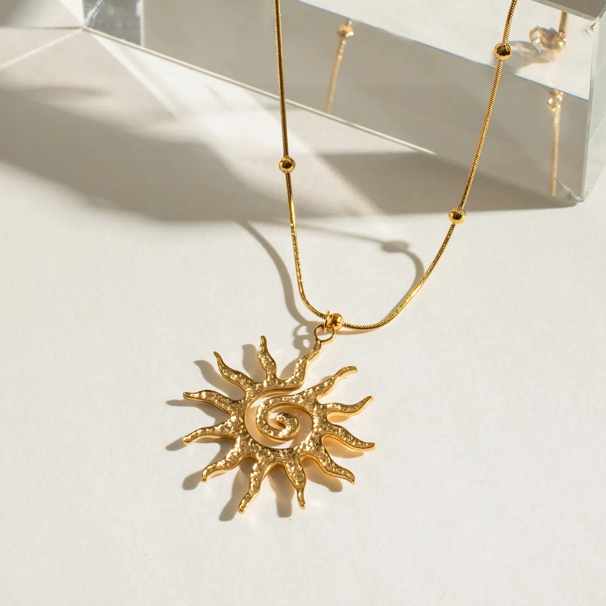 Gold necklace with sun pendant on a light background