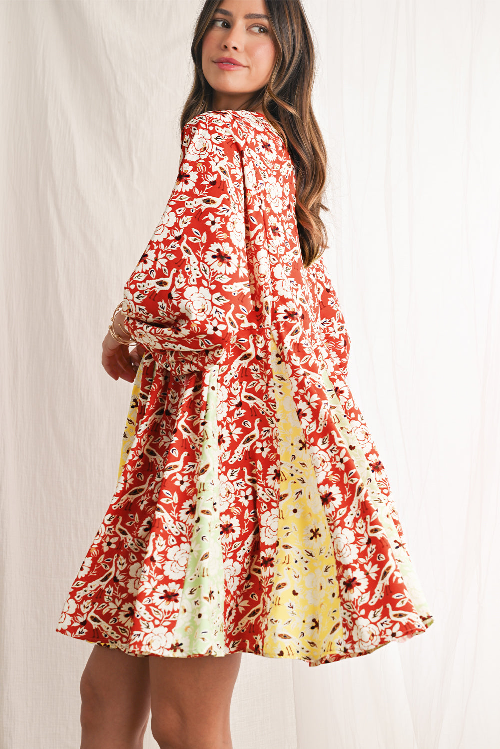 Woman wearing a red and white floral dress against a plain background
