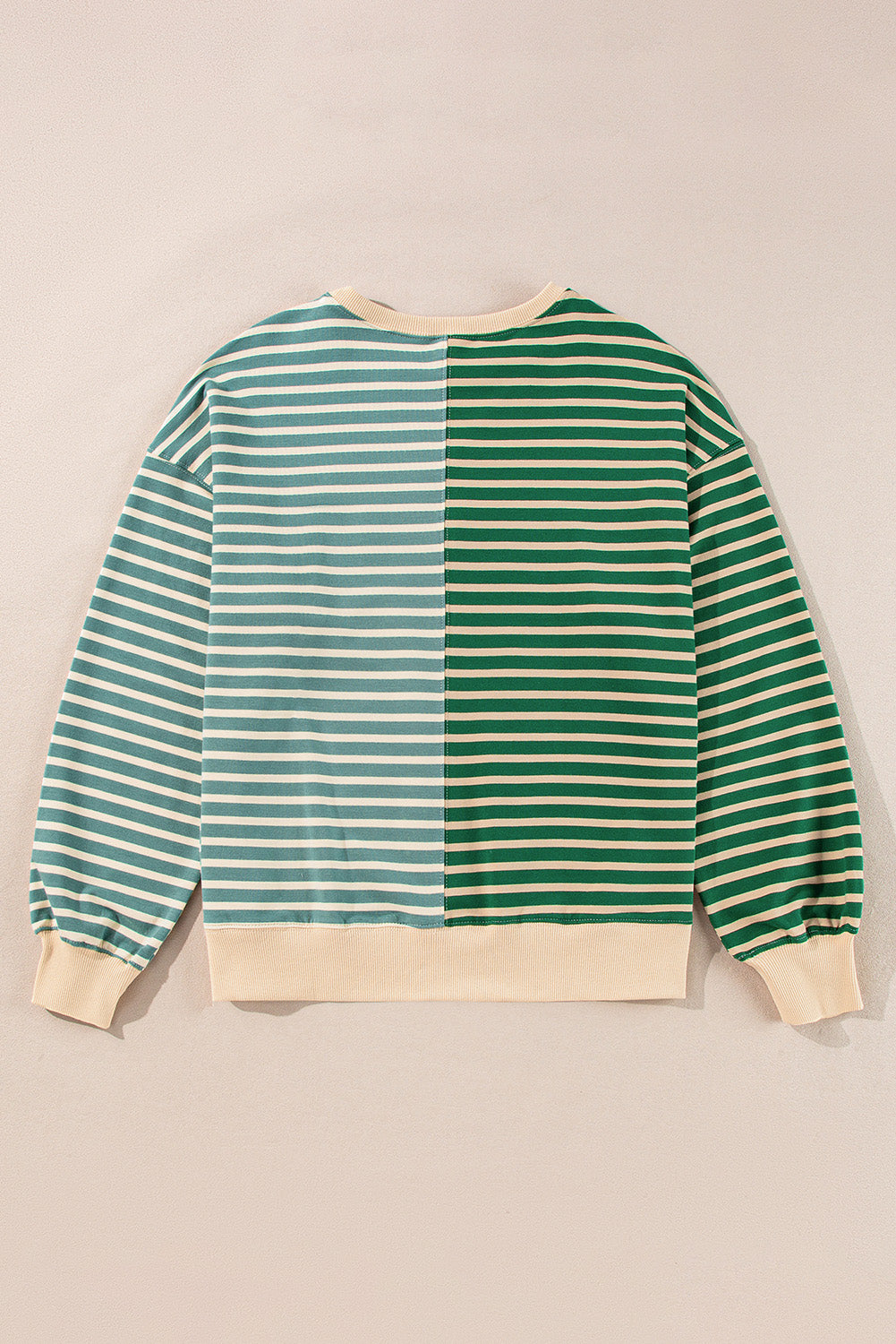 Green and white striped sweater on a beige background