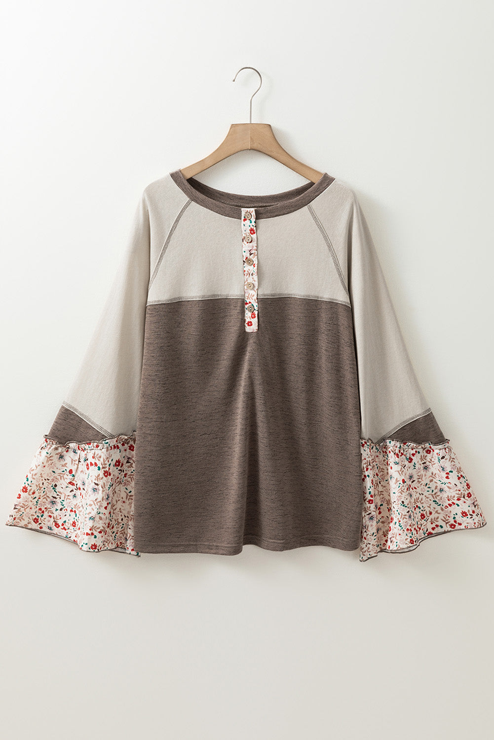 Two-tone dress with floral cuffs and hem on a wooden hanger against a white background