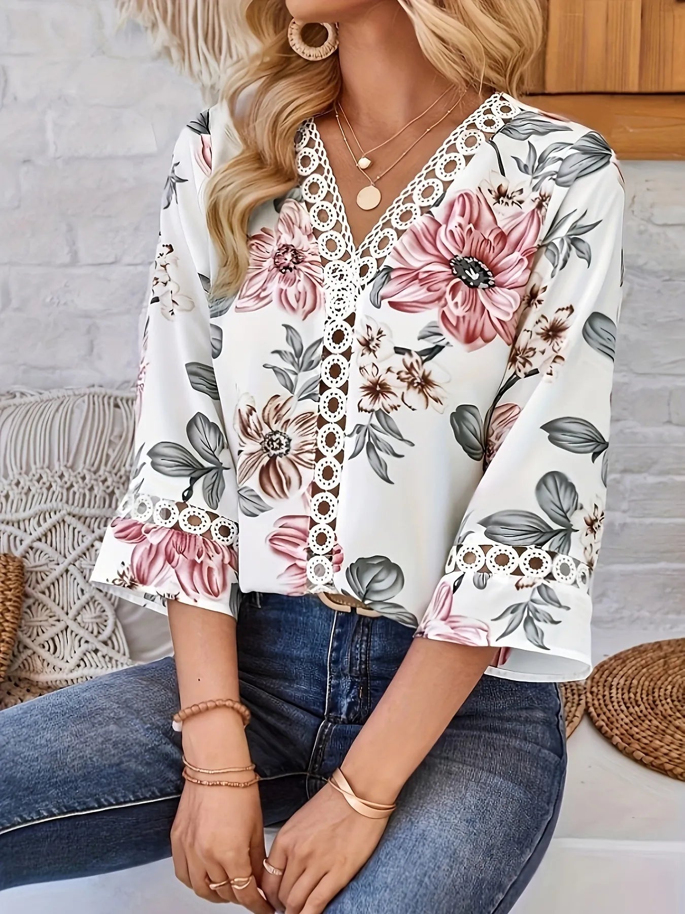 Woman wearing a floral blouse with lace details sitting on a couch.