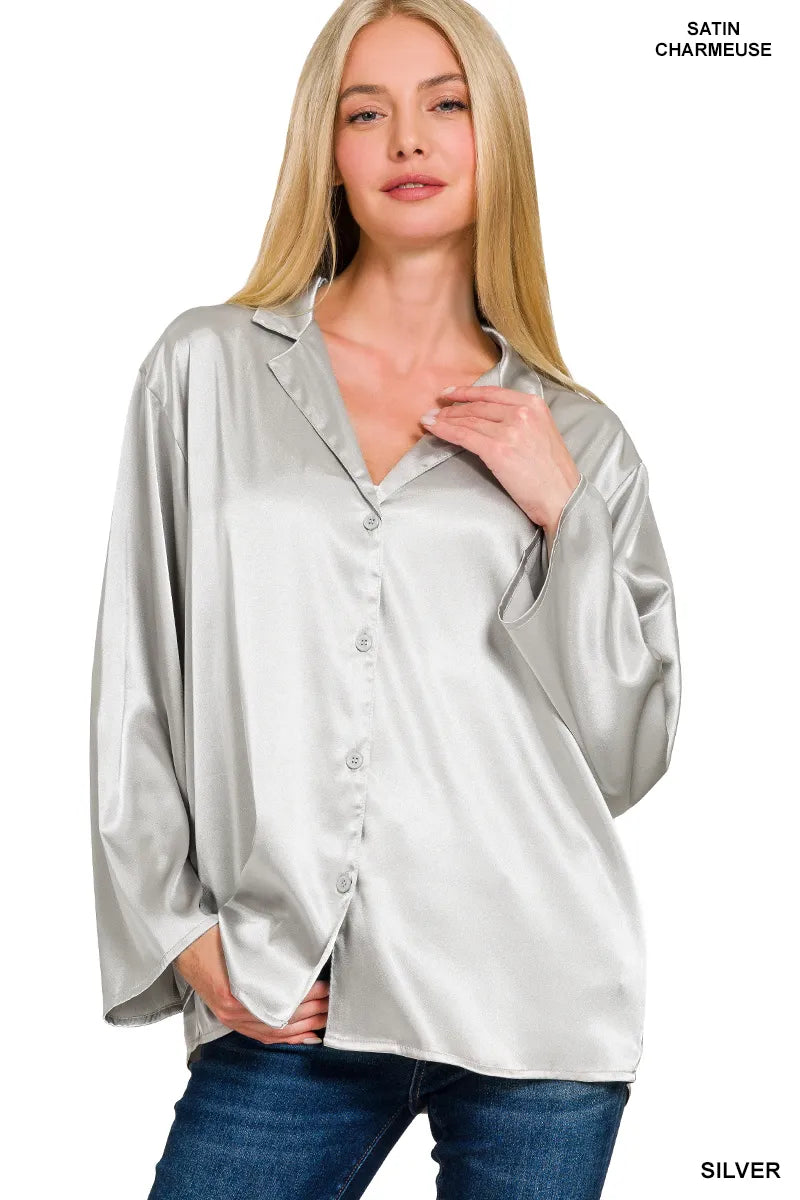 Woman wearing a silver satin blouse with a plain background