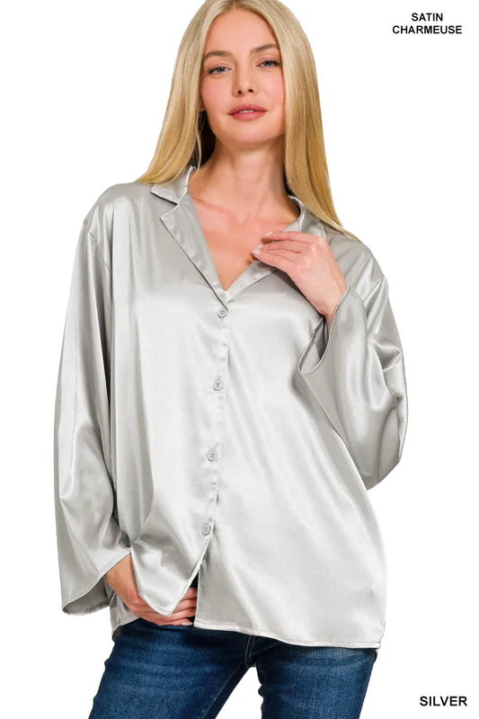 Woman wearing a silver satin blouse with a plain background