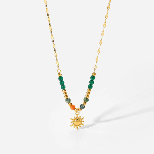 Necklace with green and gold beads and a sunflower pendant on a white background