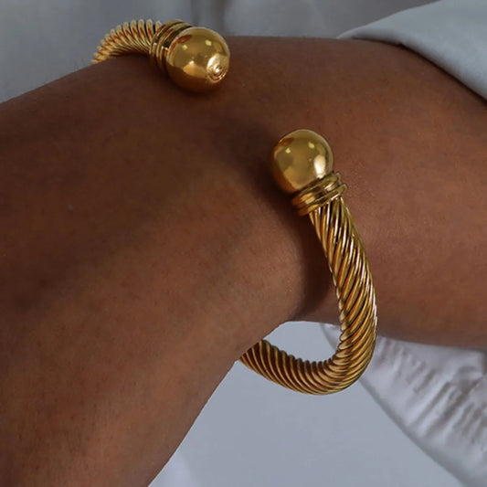 Gold hoop earrings on a person's ear with a plain background